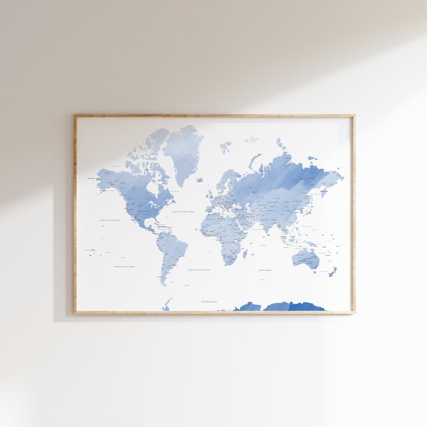 Blue watercolour world map wall art in a wood frame.