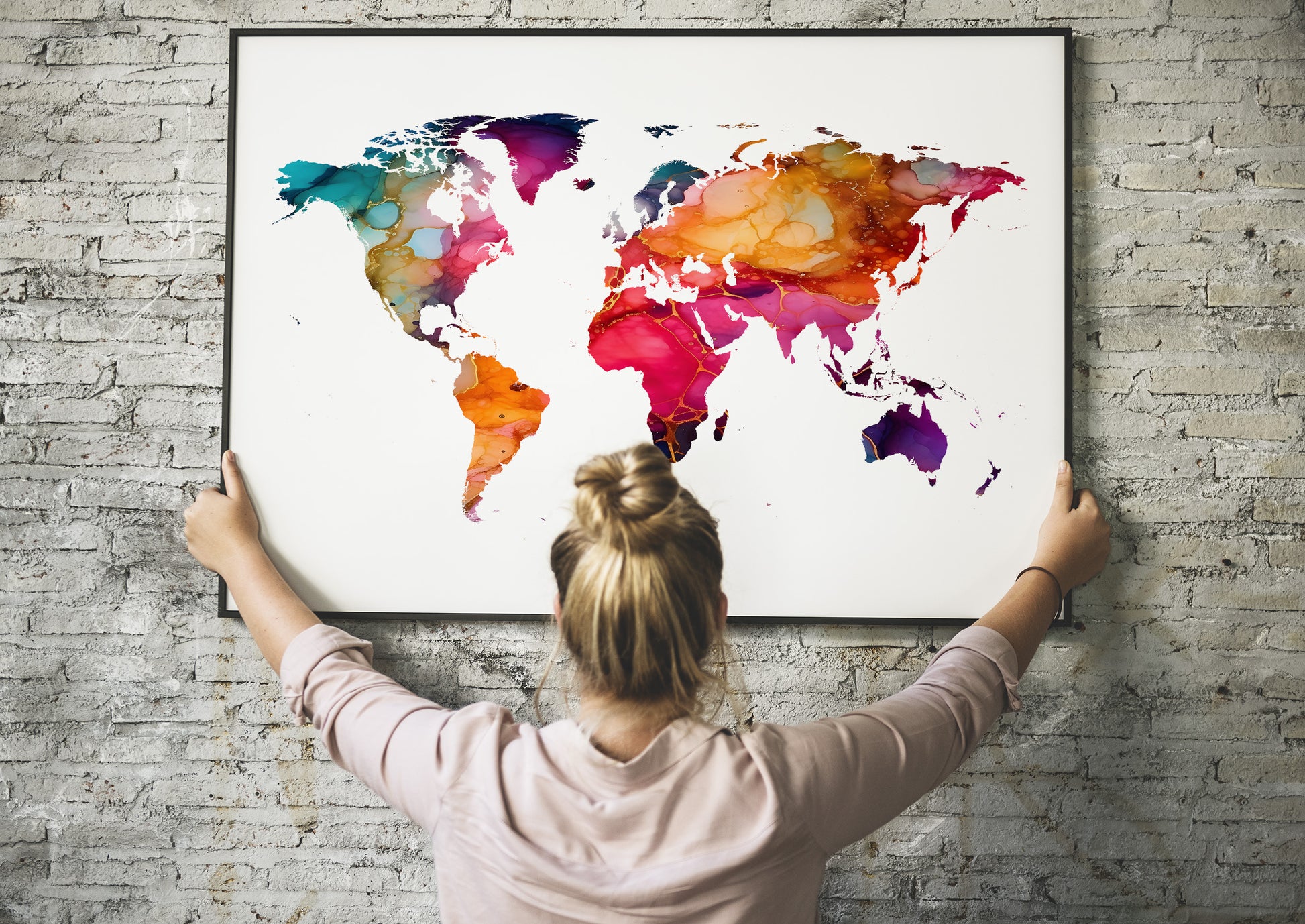 Person holding a colorful world map against a brick wall