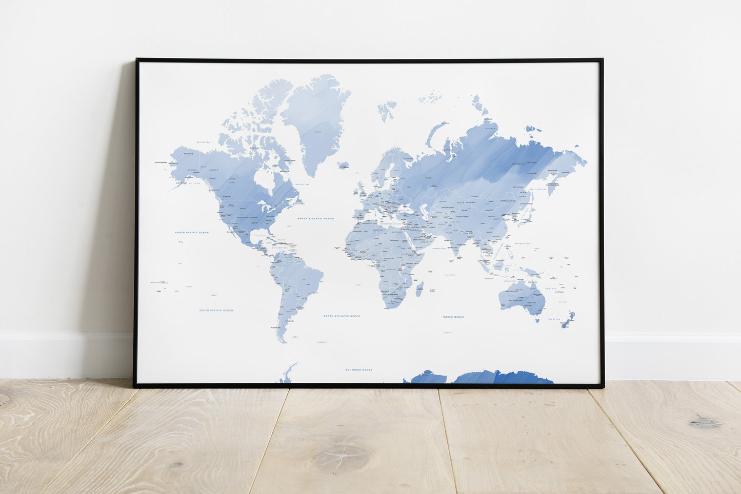 Blue watercolour world map wall art in a black metal frame.