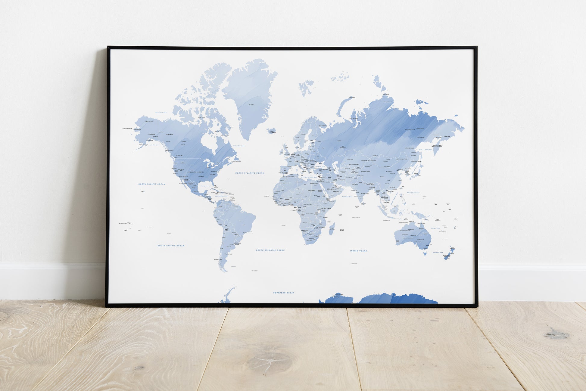 Blue watercolour world map wall art in a black metal frame.