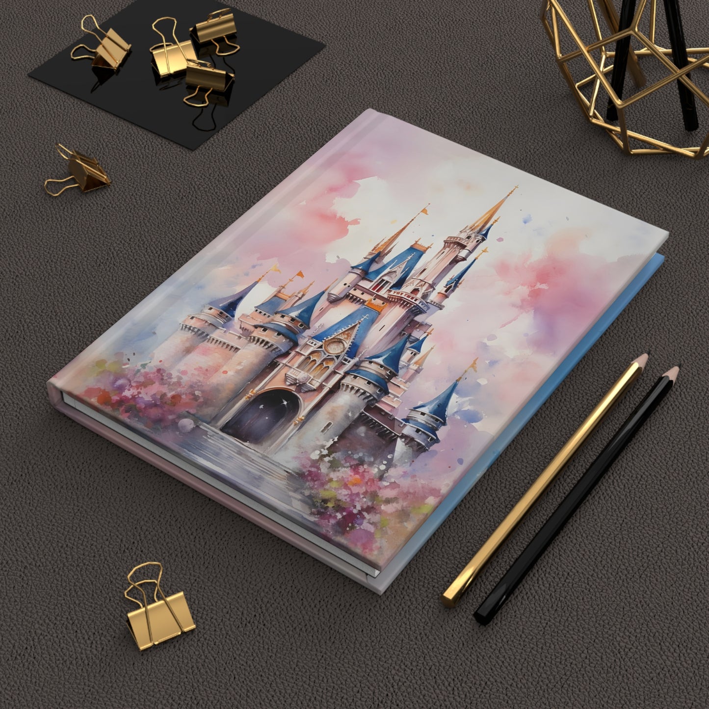 Notebook with Disney castle design on a dark surface with stationery items