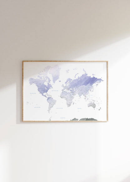 A framed world map art print with watercolor-style continents in shades of lavender, purple, and gray on a white background, hung on a light beige wall.