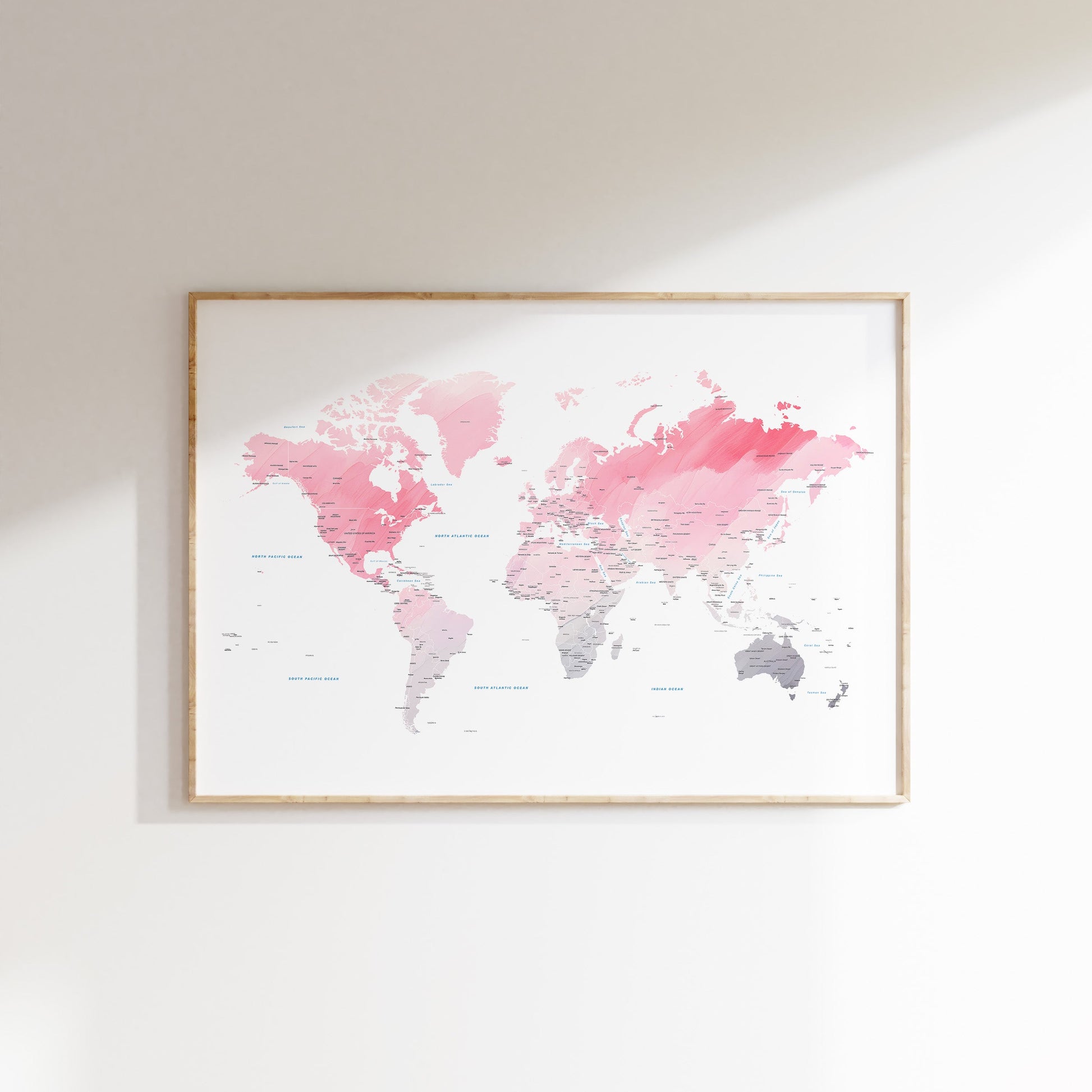 Pink watercolor world map print in a wood frame.