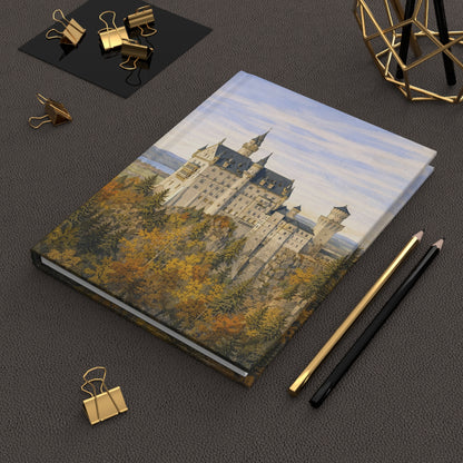 Notebook with castle illustration on a dark surface with stationery items