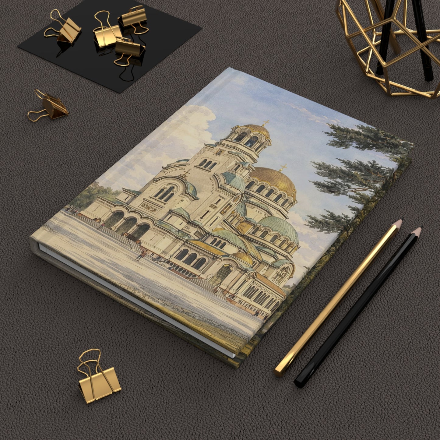 Notebook with architectural illustration of Sofia on a dark surface with office supplies