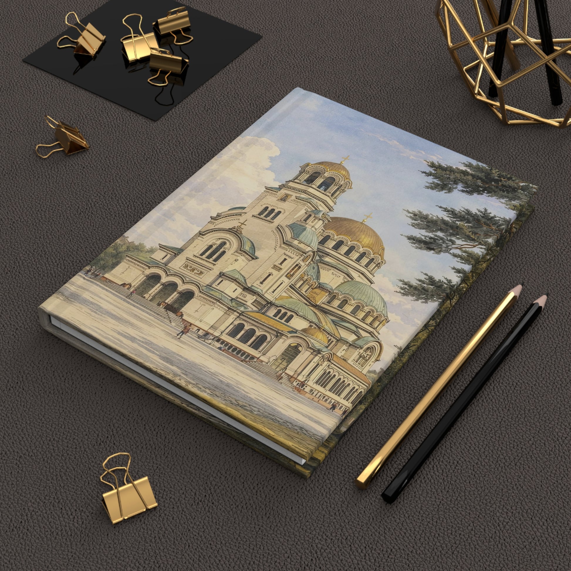 Notebook with architectural illustration of Sofia on a dark surface with office supplies