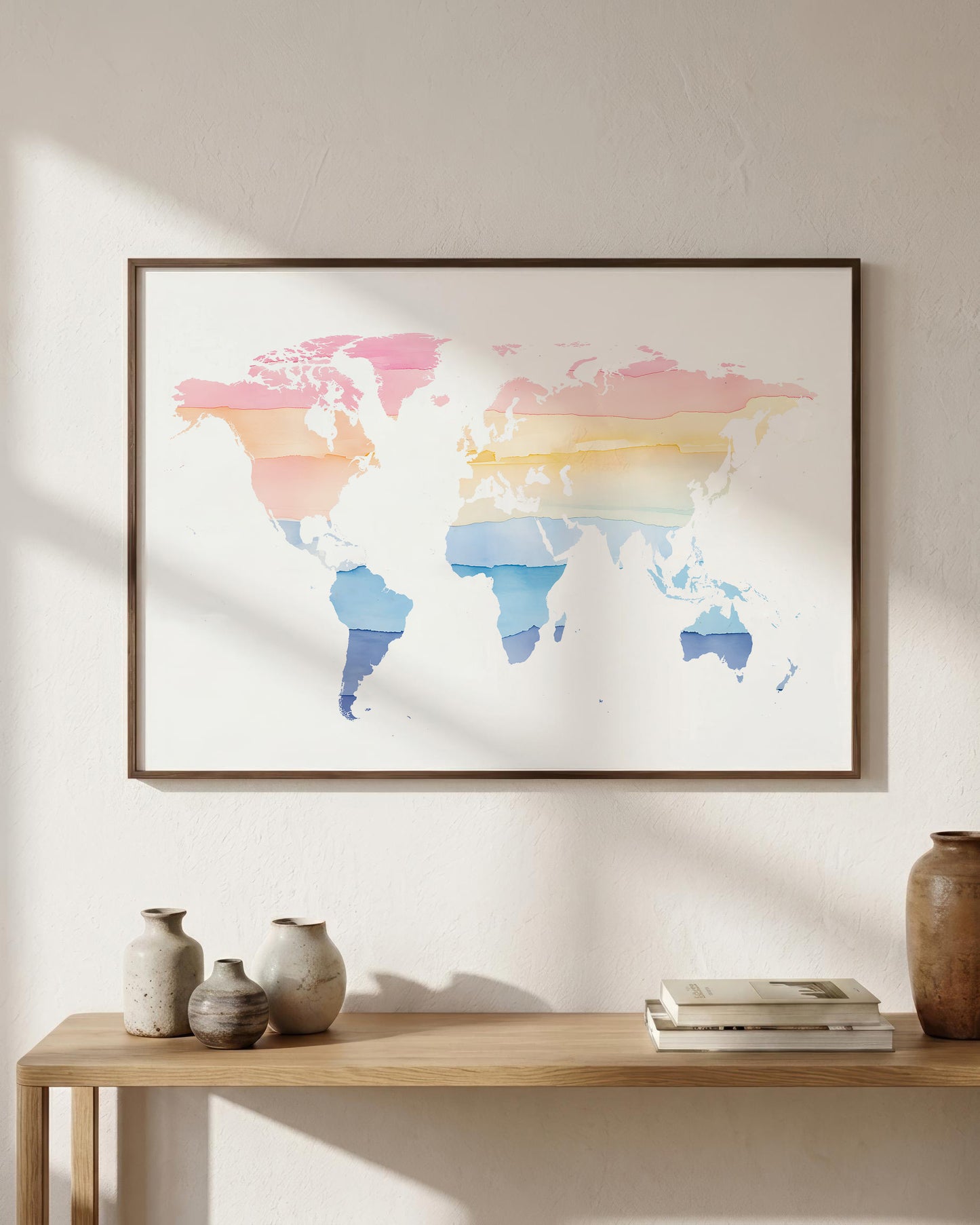 A framed world map art print with a pastel watercolor design hangs on a textured beige wall above a wooden console table with decorative vases and books.