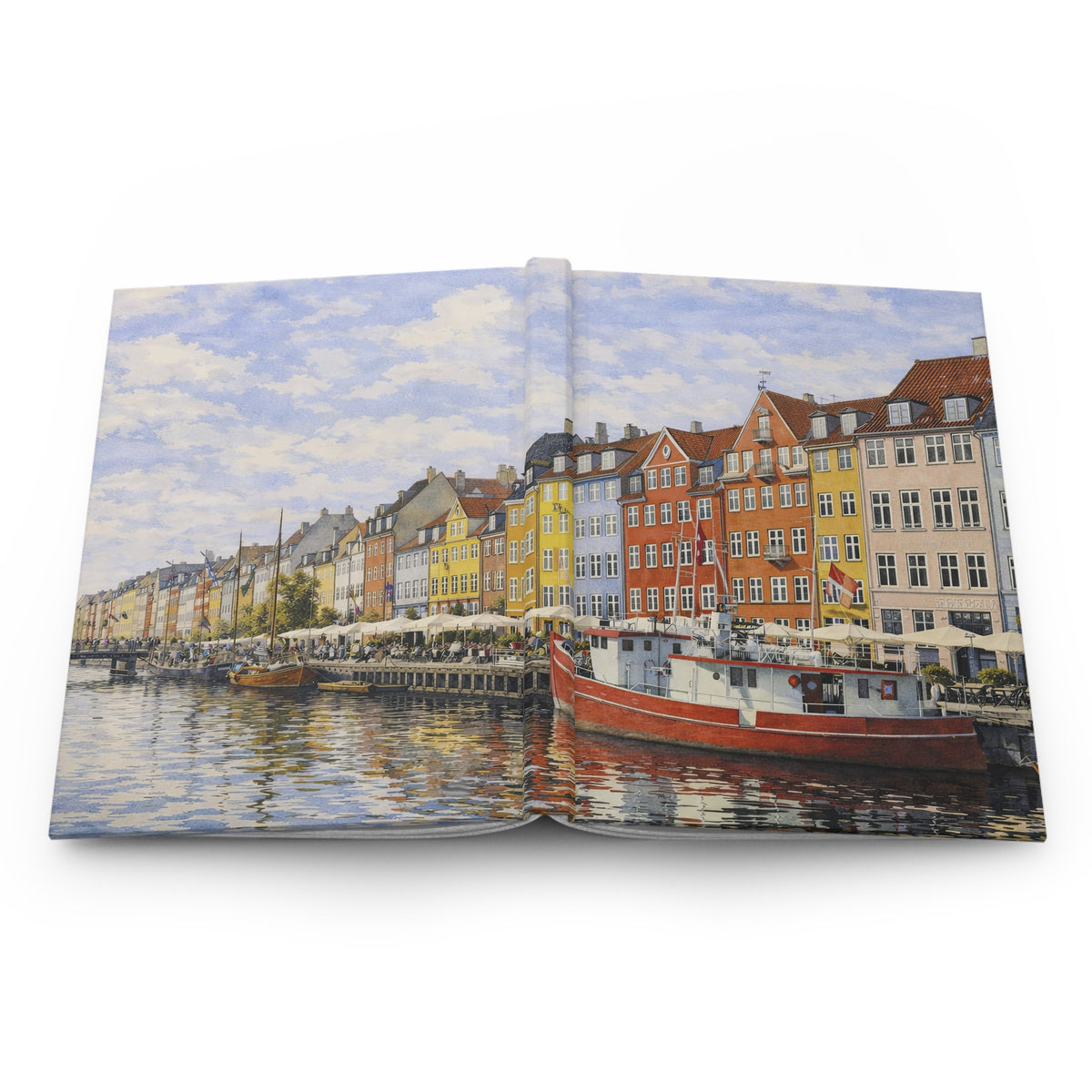An open hardcover book displaying a colorful watercolor painting of a European canal scene with buildings, boats, and reflections, photographed against a clean white background.