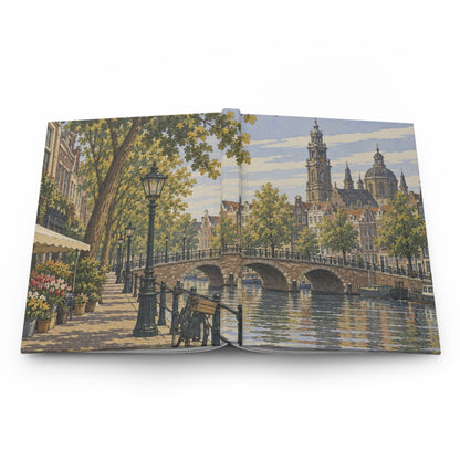 An open art print or book displaying a scenic painting of a Dutch canal with a stone bridge, trees, buildings, and a church tower, photographed against a plain white background.
