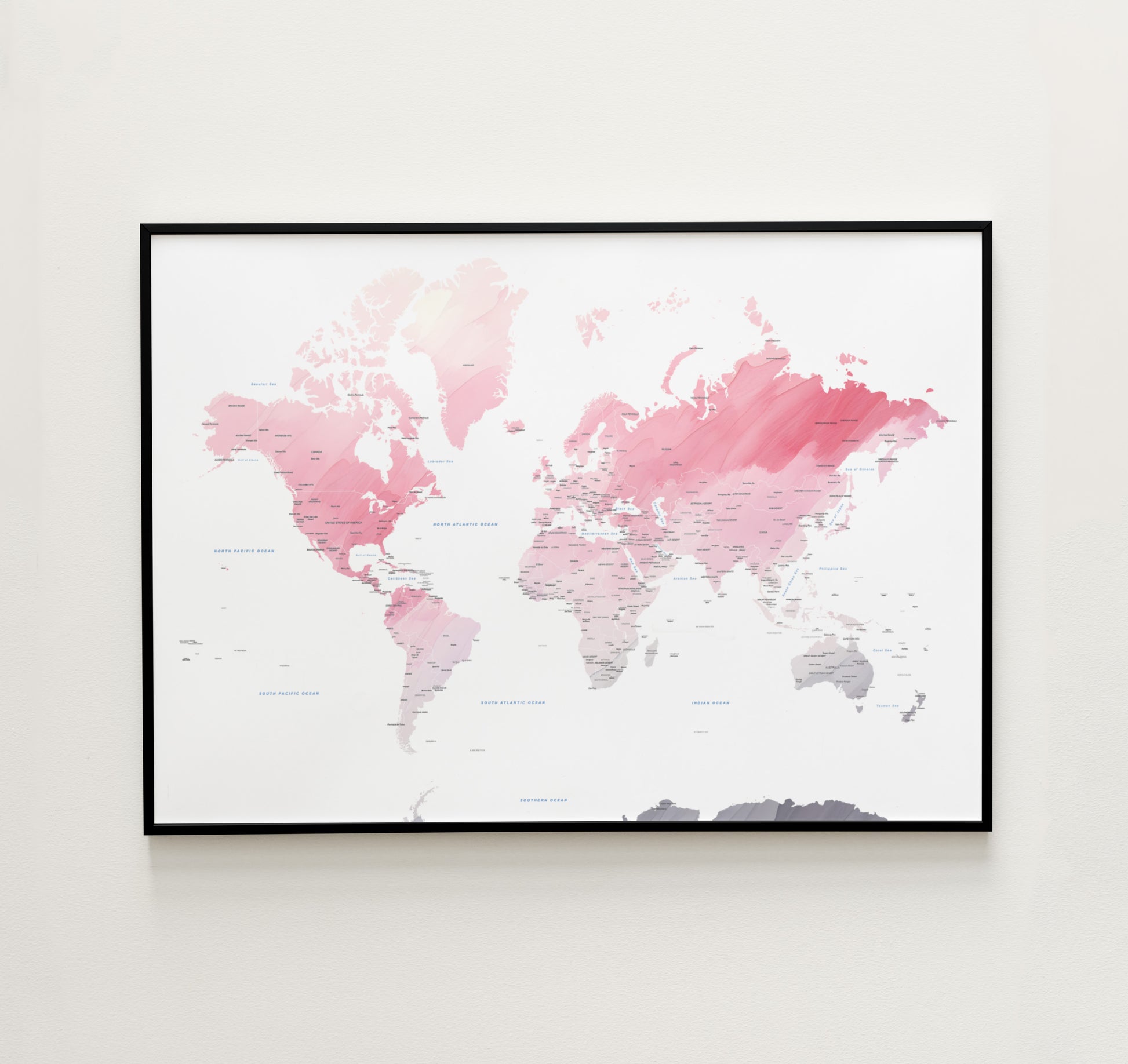 Watercolor world map print in a black metal frame.