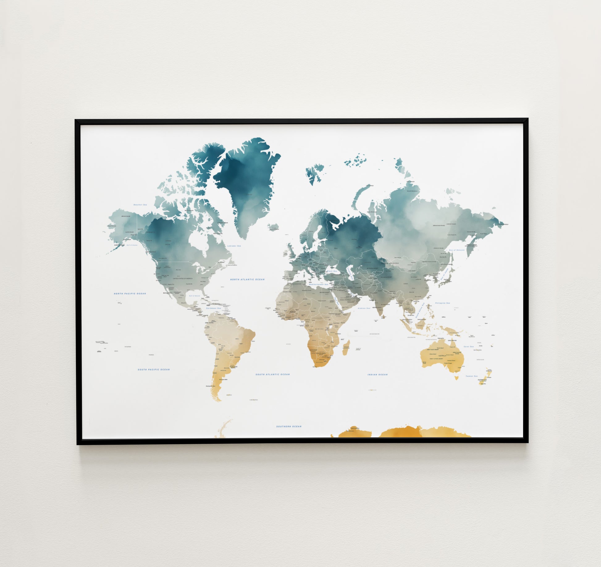 A framed world map art print with watercolor-style continents in teal, blue, beige, and gold tones, displayed on a light neutral wall.