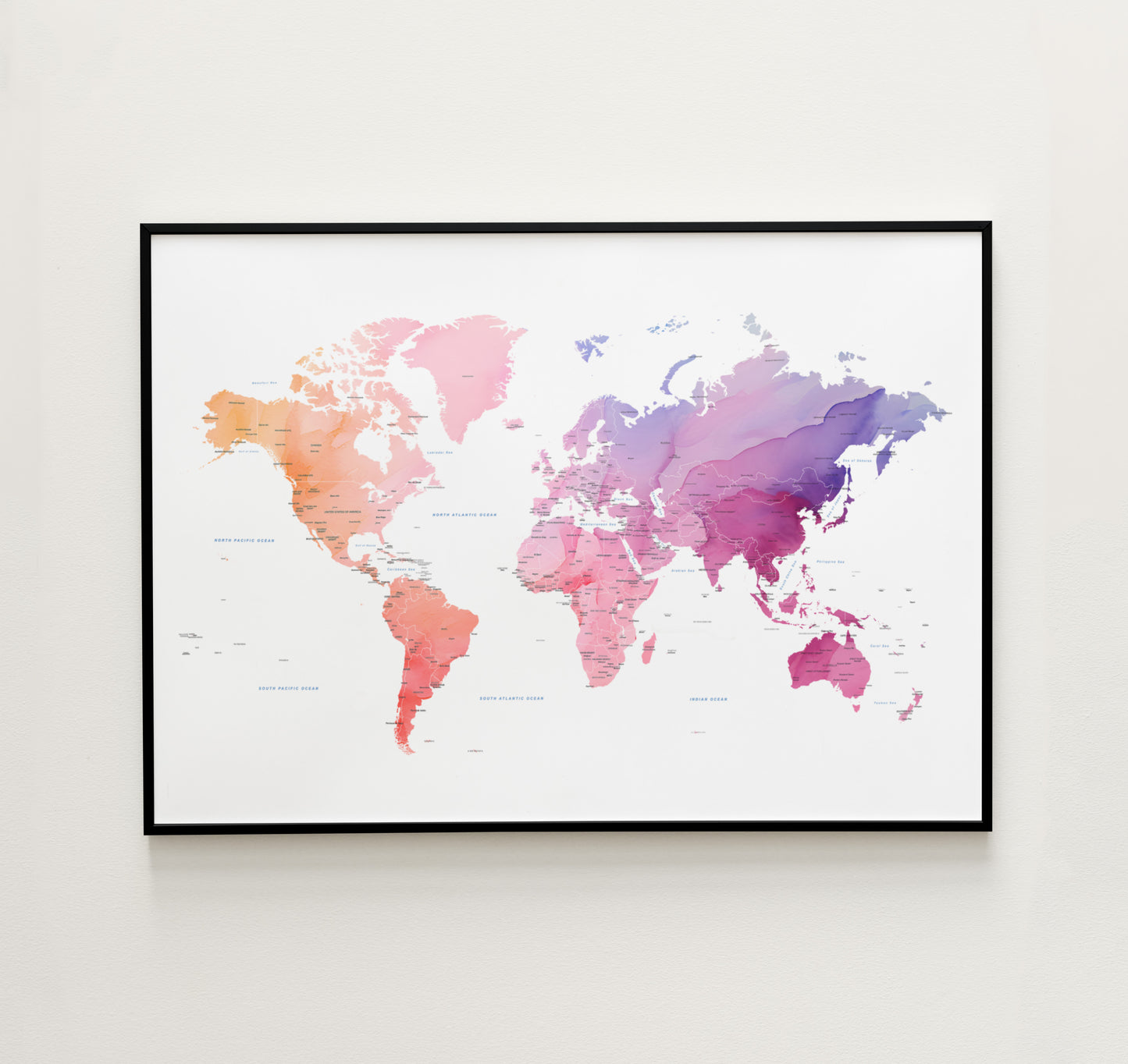 Watercolor world map art print in a black metal frame.