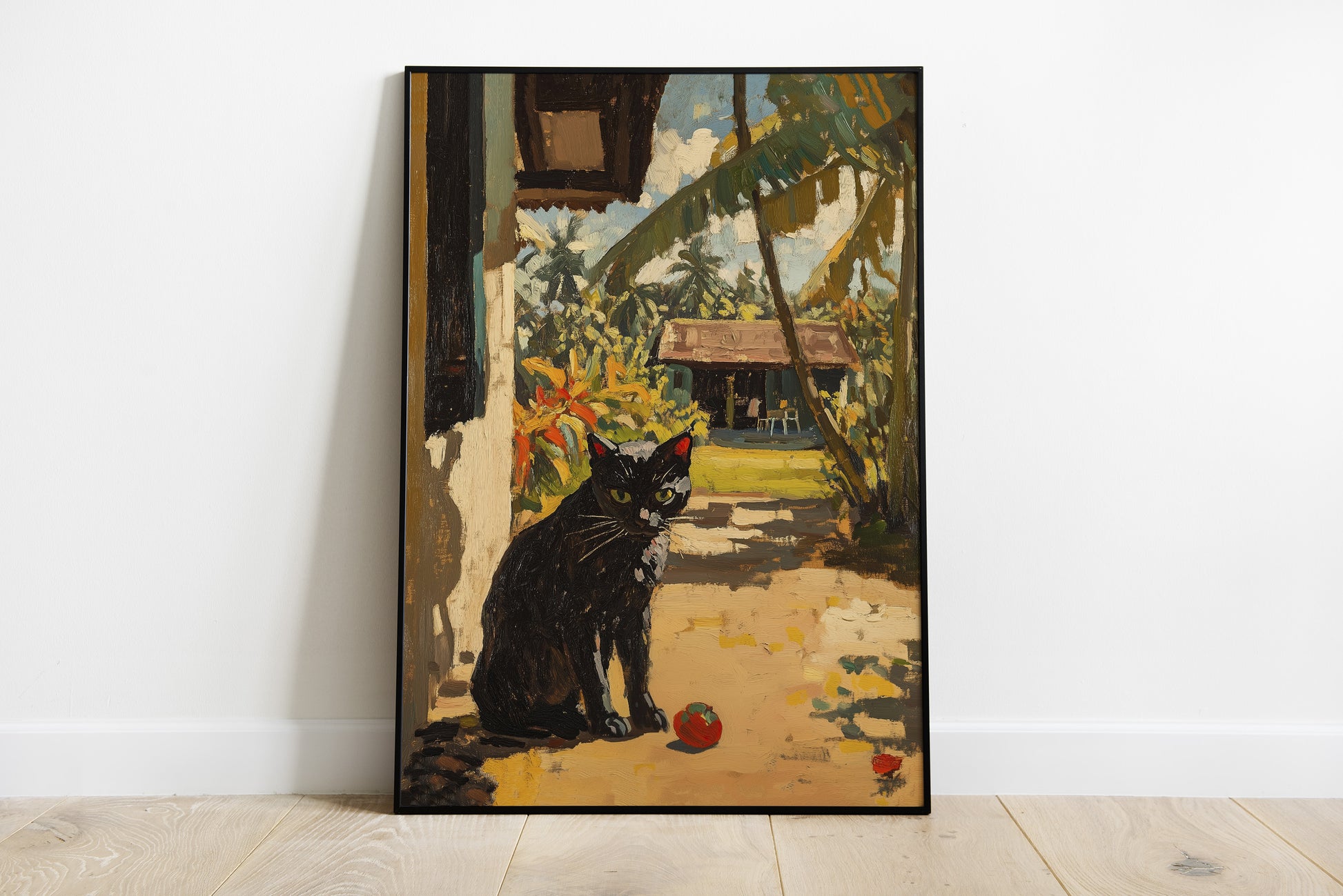 A framed vertical painting leaning against a white wall on a light wood floor. The artwork depicts a black cat sitting in a sunlit courtyard with palm leaves, a house, and small red balls on the ground.