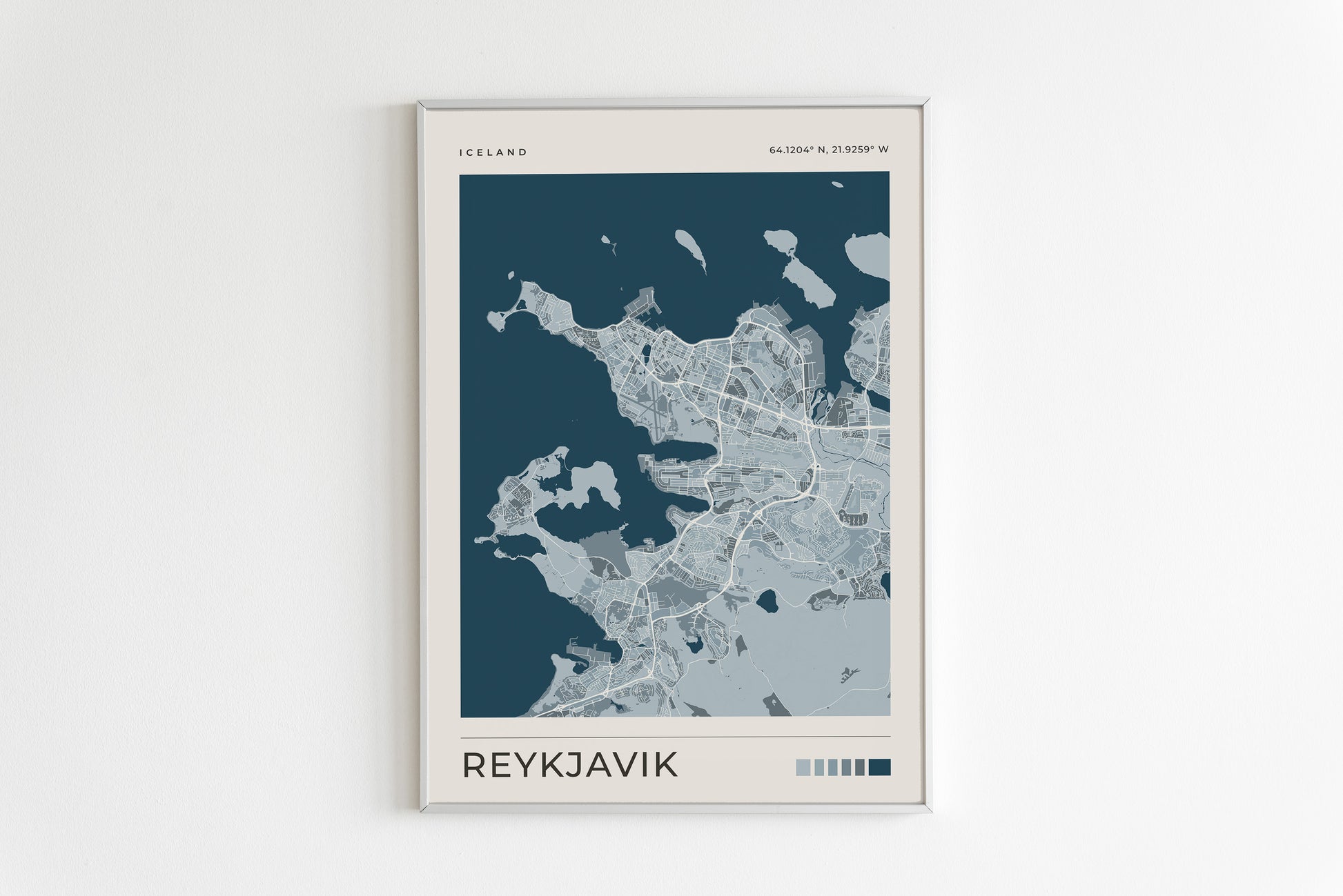 A minimalist framed map print of Reykjavík, Iceland, featuring a dark teal and light gray city layout with the text 'ICELAND' at the top and 'REYKJAVIK' at the bottom, displayed on a clean white wall.