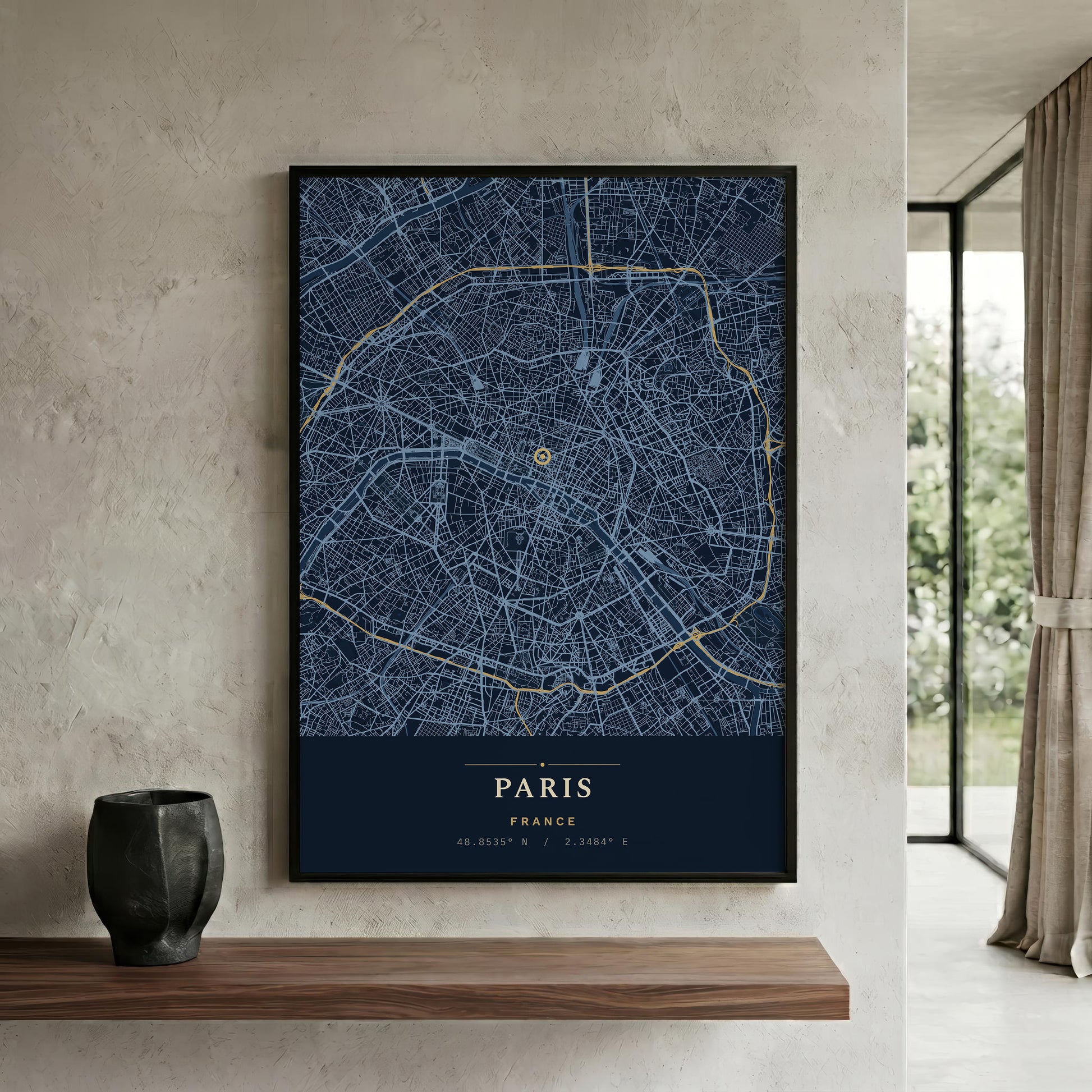 A framed Paris city map poster with a dark navy background, white street lines, and gold route details, displayed on a textured beige wall above a wooden shelf in a modern interior.