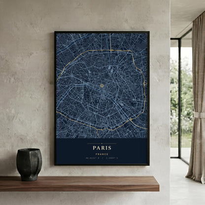A framed Paris city map poster with a dark navy background, white street lines, and gold route details, displayed on a textured beige wall above a wooden shelf in a modern interior.