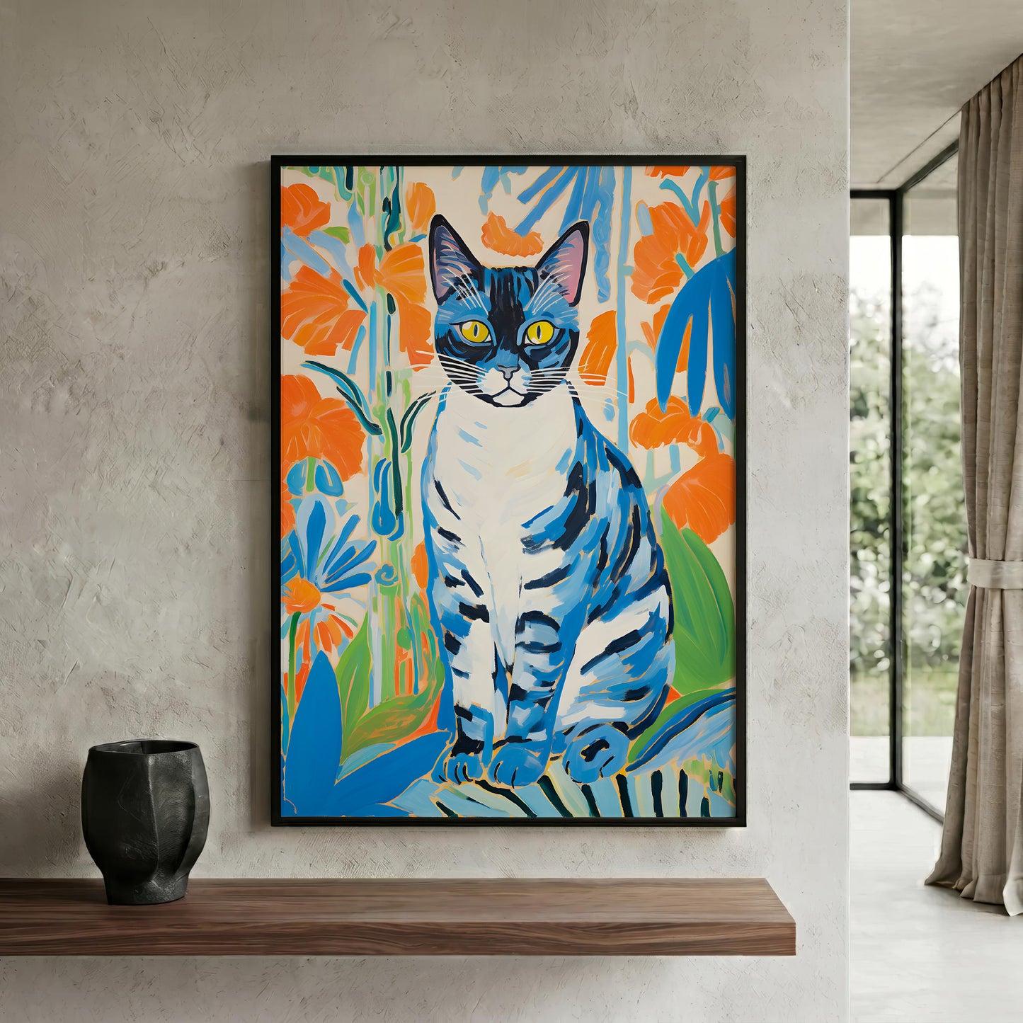 A framed vertical canvas print of a stylized blue cat with orange flowers, displayed on a textured light gray wall above a wooden shelf with a black vase.