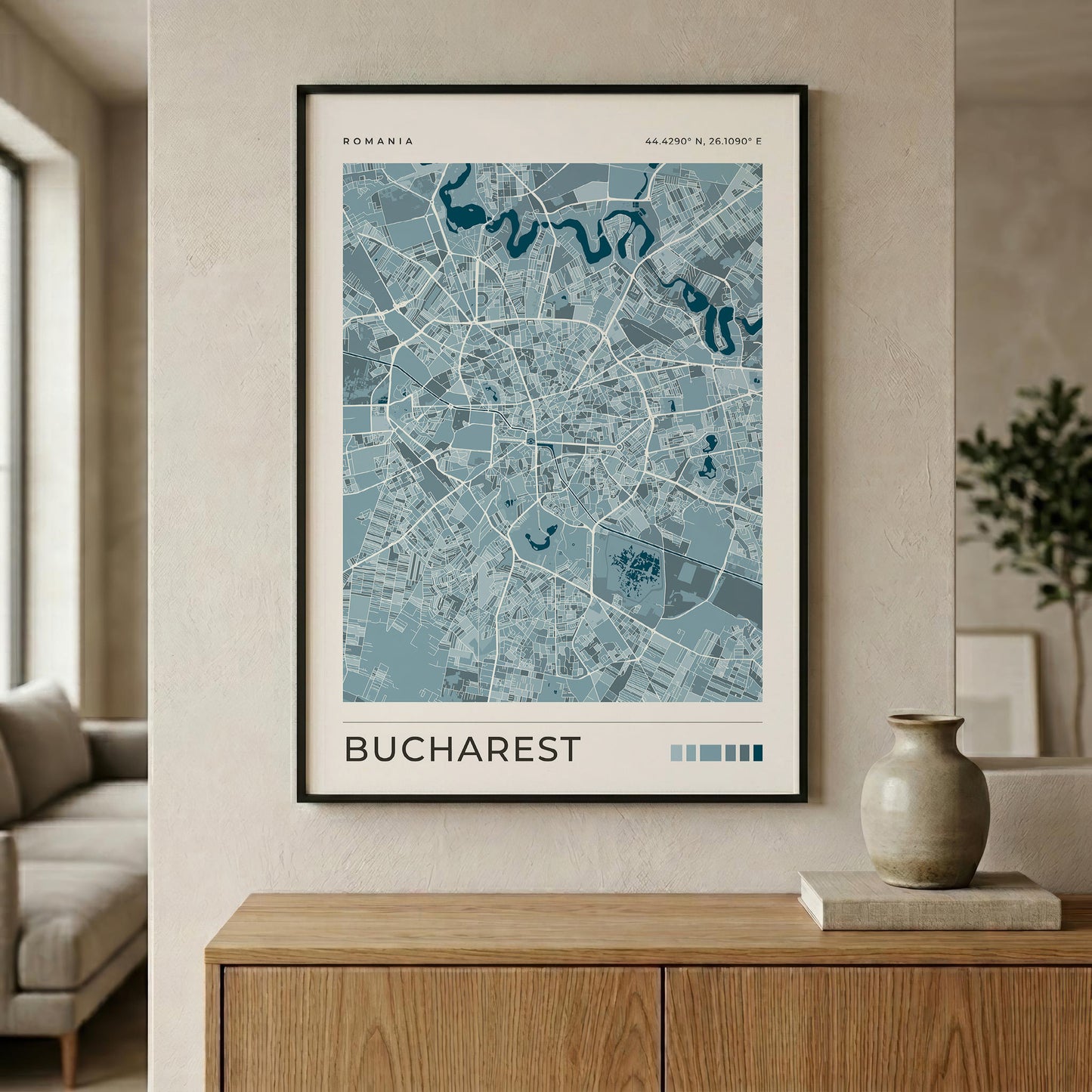 A framed minimalist map poster of Bucharest, Romania, displayed on a beige wall above a wooden console table in a modern living room setting.