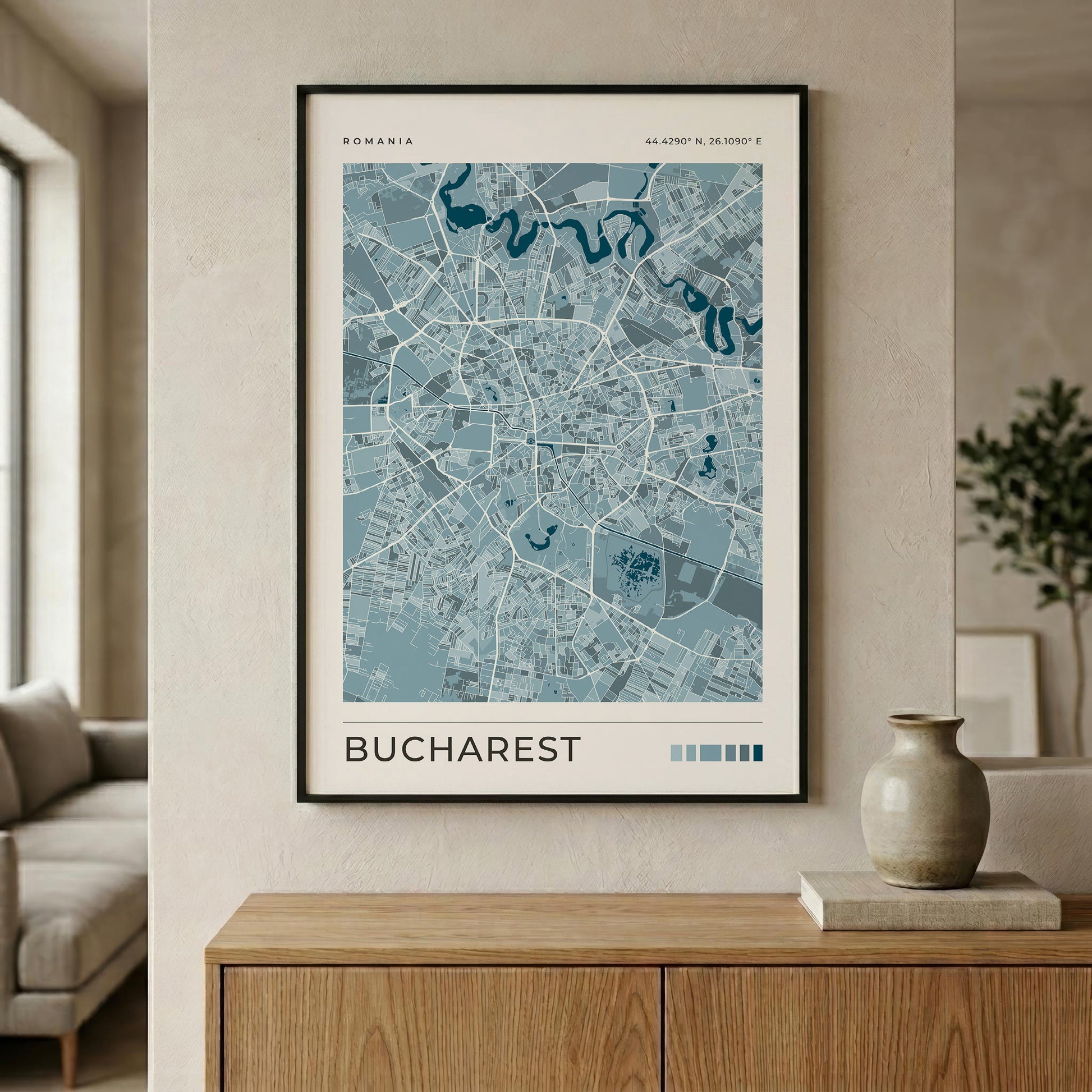 A framed minimalist map poster of Bucharest, Romania, displayed on a beige wall above a wooden console table in a modern living room setting.