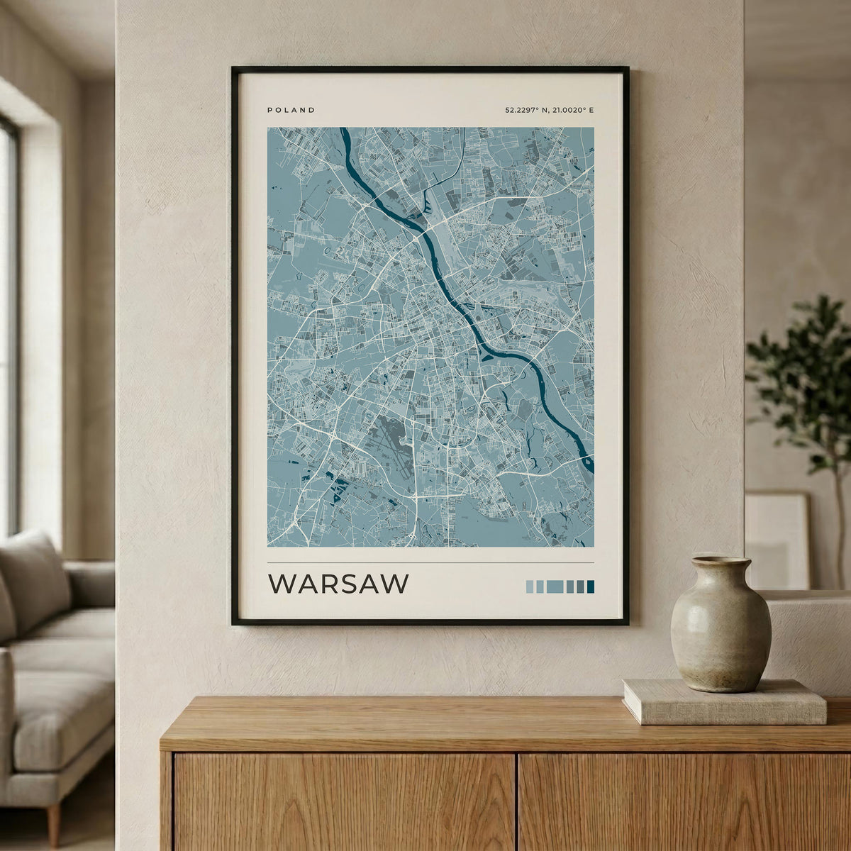 A framed city map poster of Warsaw, Poland, displayed on a beige wall above a wooden console table in a modern living room setting.