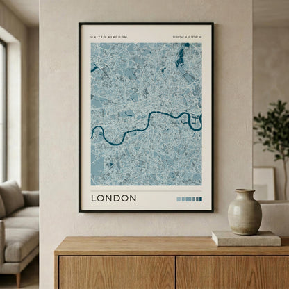 A framed London city map print with a light blue and white street pattern and a dark blue river, hanging on a beige wall above a wooden console table in a modern living room setting.