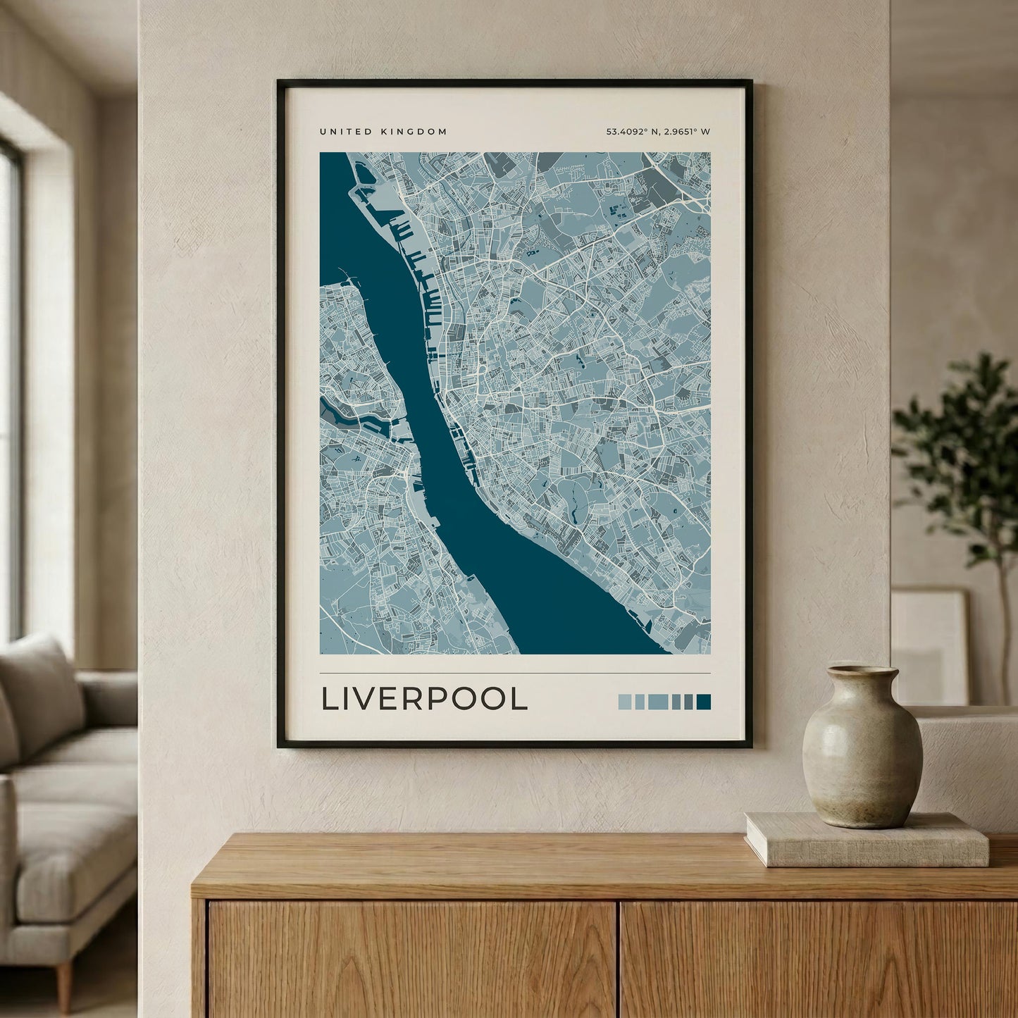 A framed map print of Liverpool, United Kingdom, displayed on a beige wall above a wooden console table in a modern living room setting.