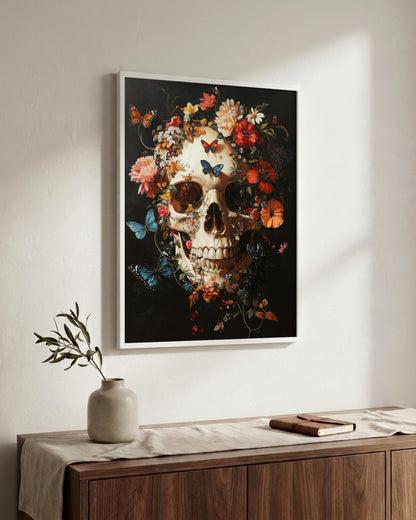 A framed wall art print featuring a decorative skull surrounded by flowers and butterflies on a dark background, displayed above a wooden console table in a styled interior setting.