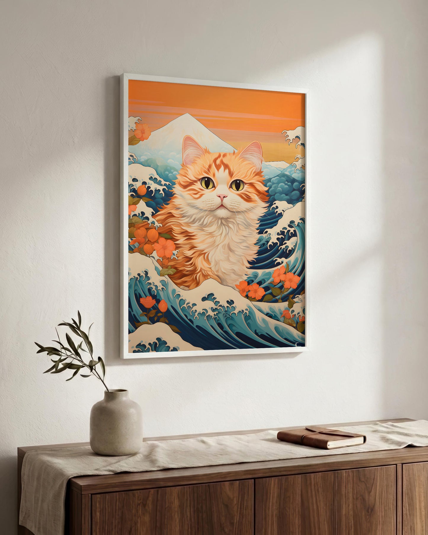 A framed wall art print featuring an orange tabby cat in a Japanese wave-and-mountaineer Hokusai style, hanging above a wooden console table with a vase and book in a styled interior.