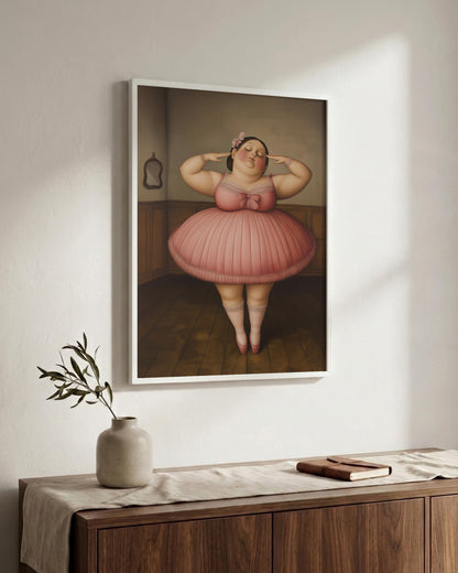 A framed art print depicting a stylized, cartoonish figure in a pink tutu standing in a room, displayed on a white wall above a wooden console table with a vase and book.