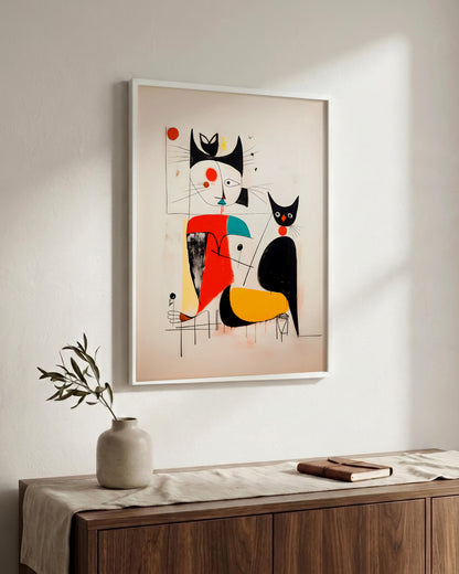 A framed abstract art print featuring stylized black and red cat-like figures on a beige background, hanging on a white wall above a wooden console table with a vase and book.