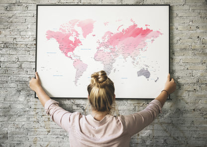 Pink watercolor world map wall art in a black metal frame.