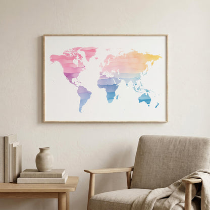 A framed world map art print with a watercolor gradient in pink, purple, blue, and yellow tones, displayed on a light beige wall above a modern armchair and side table.