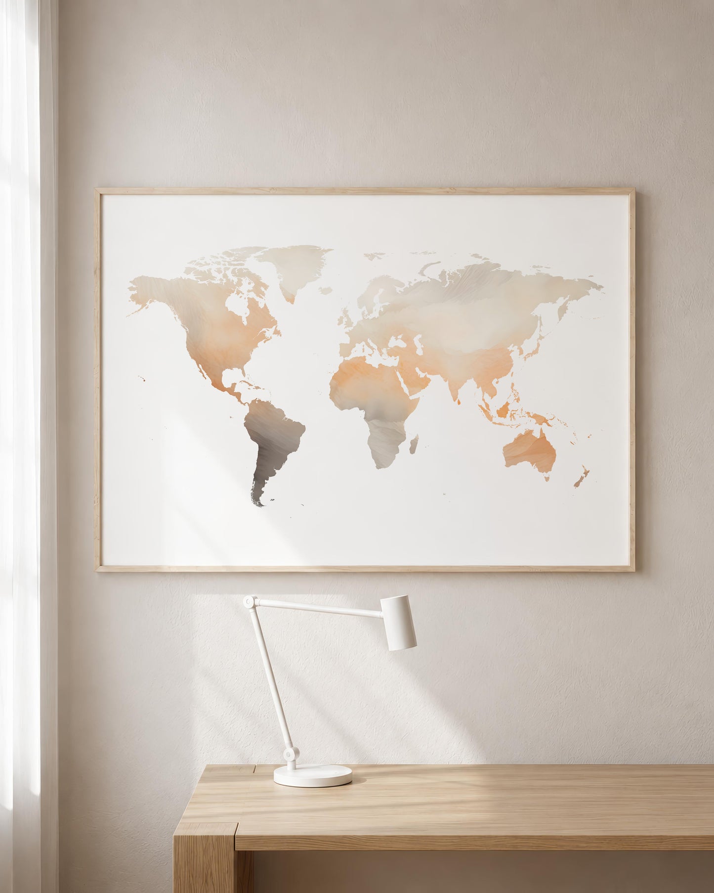 A framed world map art print with a watercolor design in muted beige, gray, and terracotta tones, hanging on a light beige wall above a wooden desk with a white desk lamp.