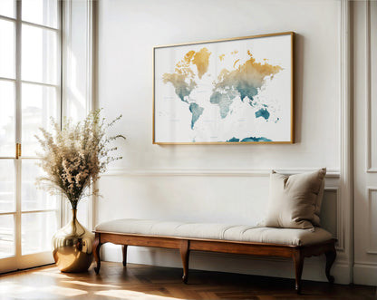 A framed world map art print hangs on a white wall above a wooden bench with a beige cushion in a bright, modern room with a window and a gold vase of dried flowers.