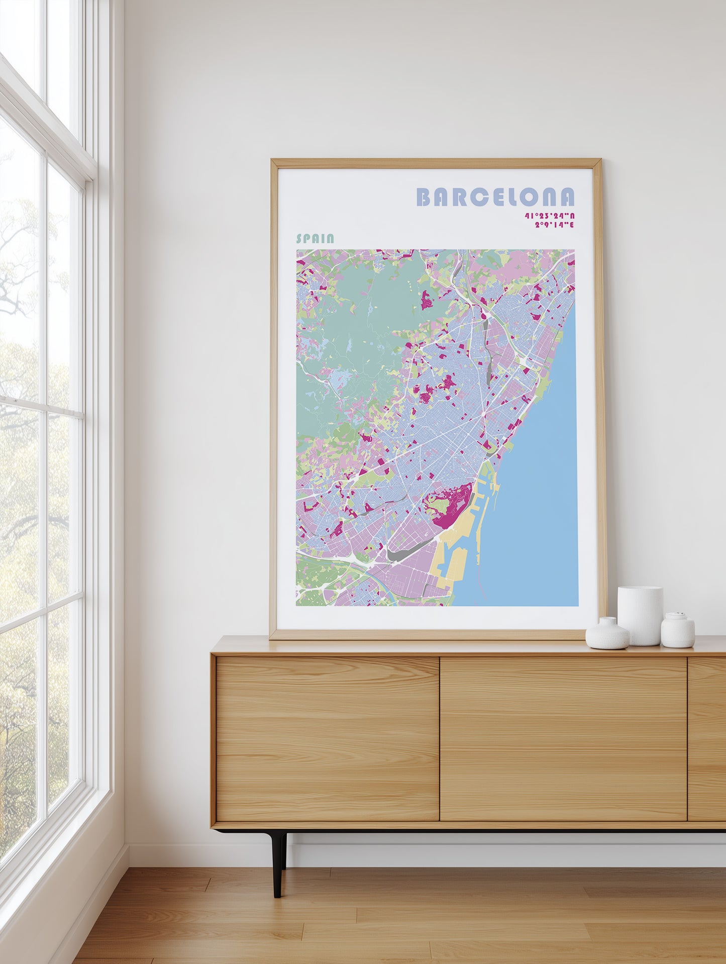 Framed map of Barcelona on a wall above a wooden cabinet.
