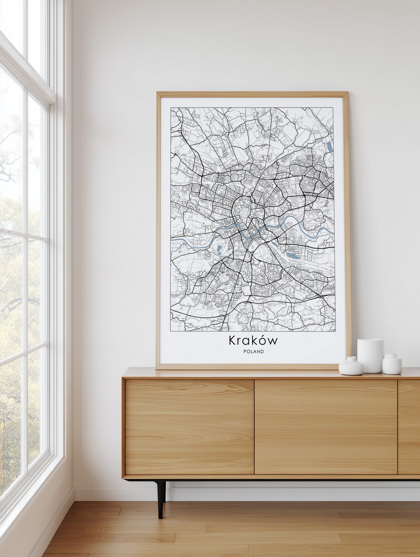 Framed map of Kraków on a wall above a wooden cabinet.