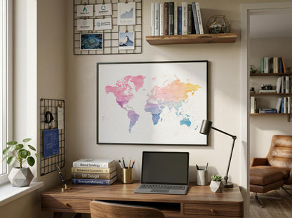 A framed world map poster with a colorful watercolor design hangs on a beige wall above a wooden desk in a styled home office setting.