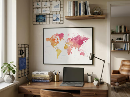 A framed world map poster with a colorful watercolor design hangs on a beige wall above a wooden desk in a styled home office setting.