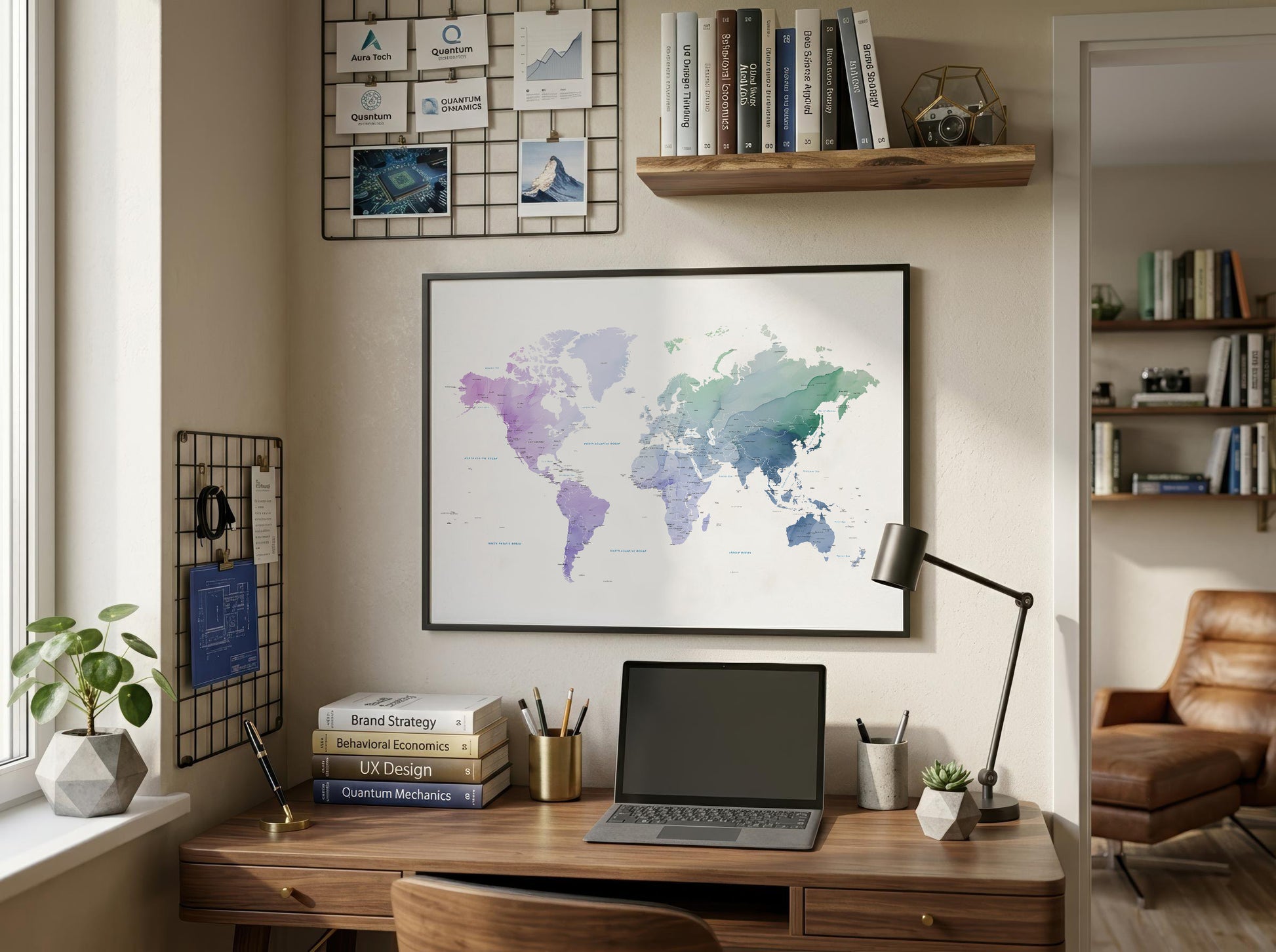 A framed world map poster with a watercolor design in shades of purple, blue, and green, displayed on a beige wall above a wooden desk in a styled home office setting.