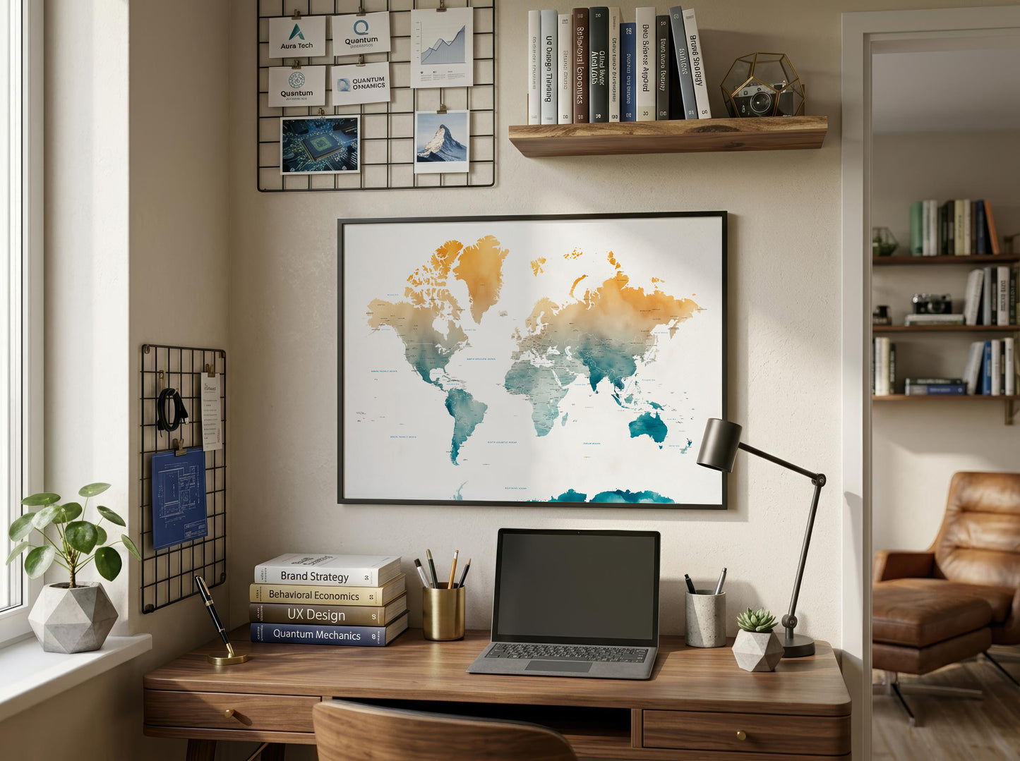 A framed world map poster with watercolor-style continents in orange, yellow, teal, and blue, displayed on a beige wall above a wooden desk in a styled home office setting.