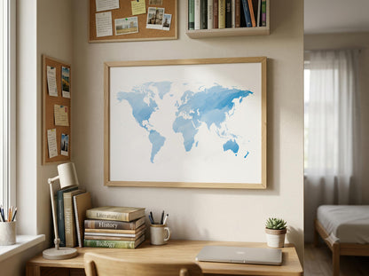 A framed world map print with blue watercolor continents hanging on a beige wall above a wooden desk in a styled home office.
