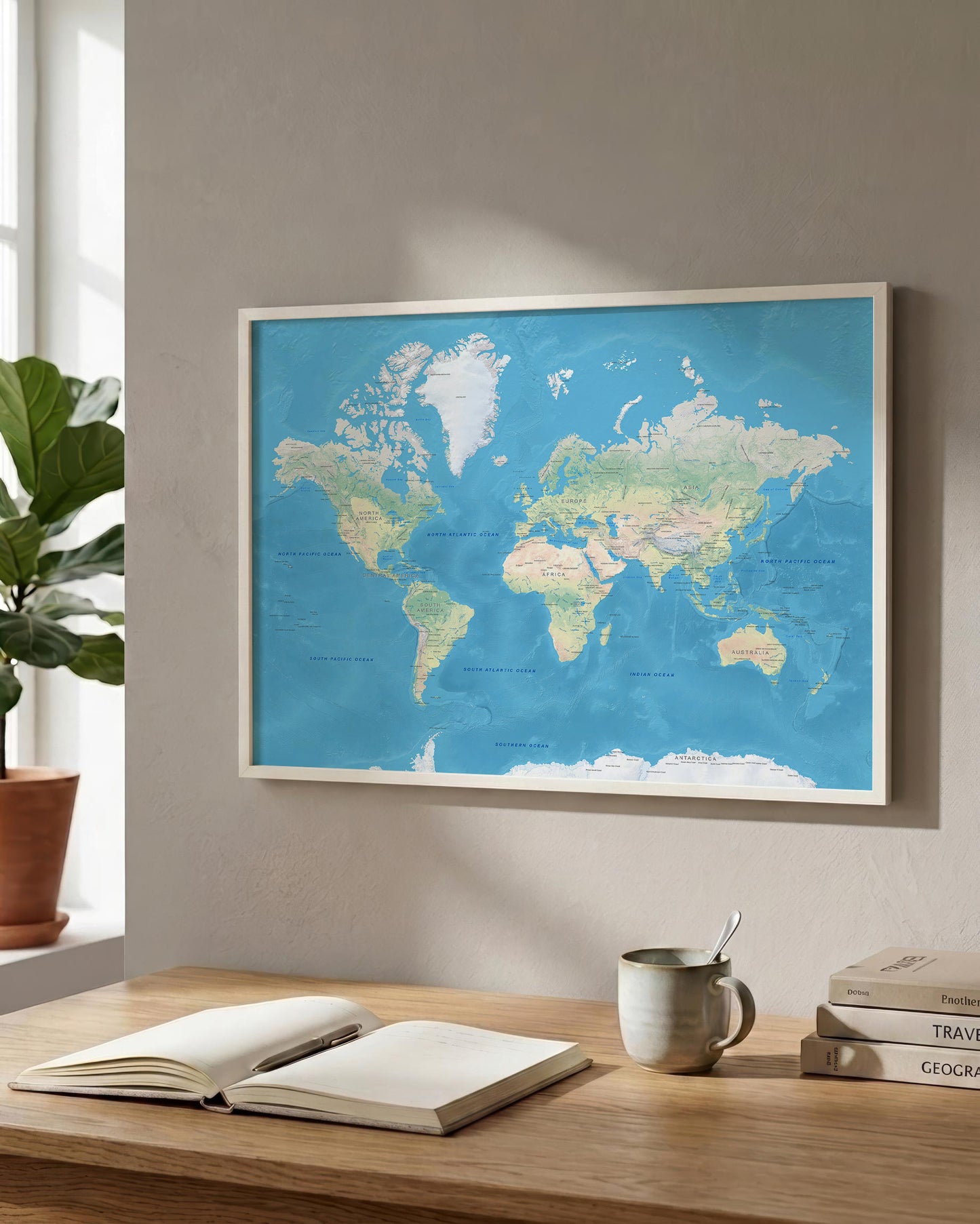 A framed world map with a blue ocean background hangs on a beige wall above a wooden desk with an open book, a mug, and stacked books. A potted plant is visible at the window on the left.