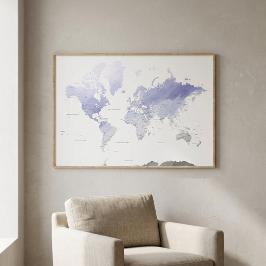 A framed world map print with watercolor-style blue and purple landmasses hangs on a light beige wall above a beige armchair in a softly lit room.
