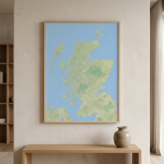 A framed vertical map print of Scotland with a light blue background and green landmasses, hanging on a beige wall above a wooden console table with a ceramic vase.
