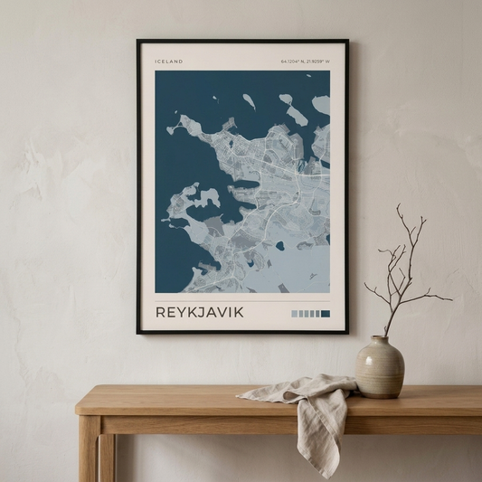A framed minimalist map poster of Reykjavík, Iceland, hanging on a textured off-white wall above a light wood console table with a ceramic vase and cloth.