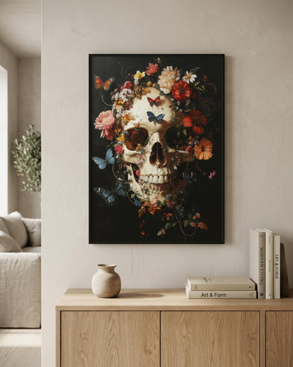 A framed wall art print featuring a detailed skull surrounded by colorful flowers and butterflies on a dark background, displayed in a modern living room setting above a light wood console table.