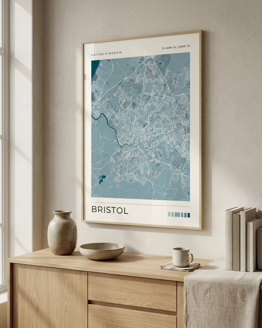 A framed city map print of Bristol, United Kingdom, displayed on a beige wall above a light wood console table with decorative ceramic vases, a bowl, and a cup.