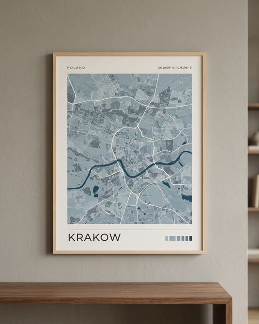 A framed minimalist map poster of Krakow, Poland, featuring a light blue and gray street layout with a dark blue river, mounted on a warm gray wall above a wooden console table.