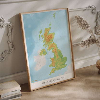 A framed topographical map poster of the United Kingdom hanging on a light-colored wall.
