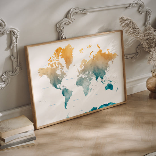 A yellow and teal watercolor world map print in a wood frame on the floor